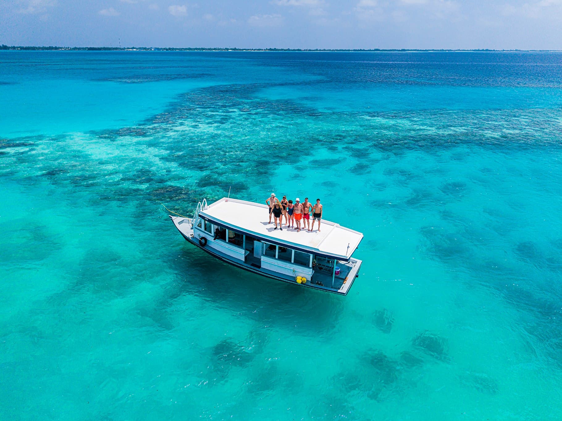 Traditional dhoni carrying guests across a turquoise Maldivian lagoon